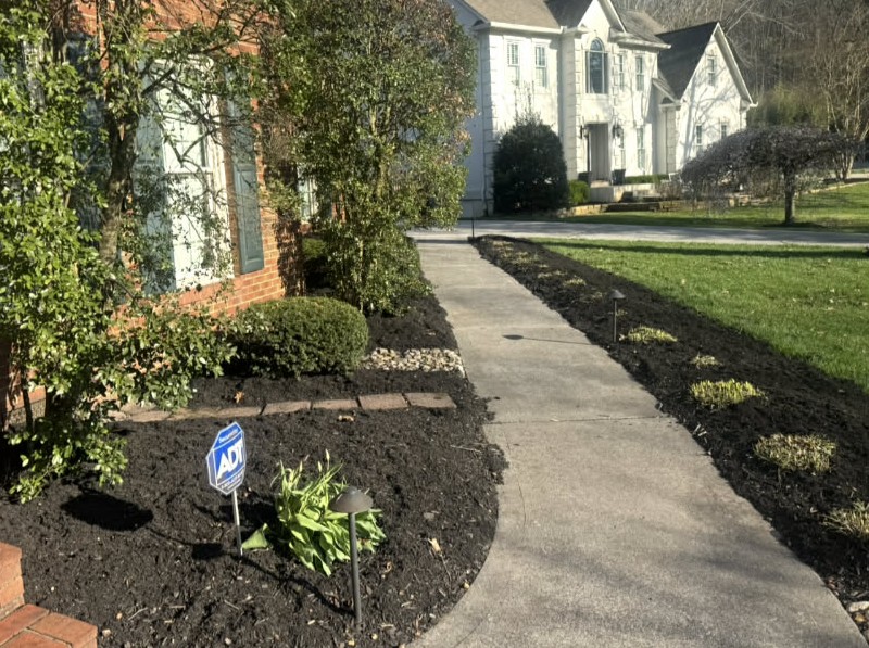 Professionally landscaped front yard with flower beds and stone borders